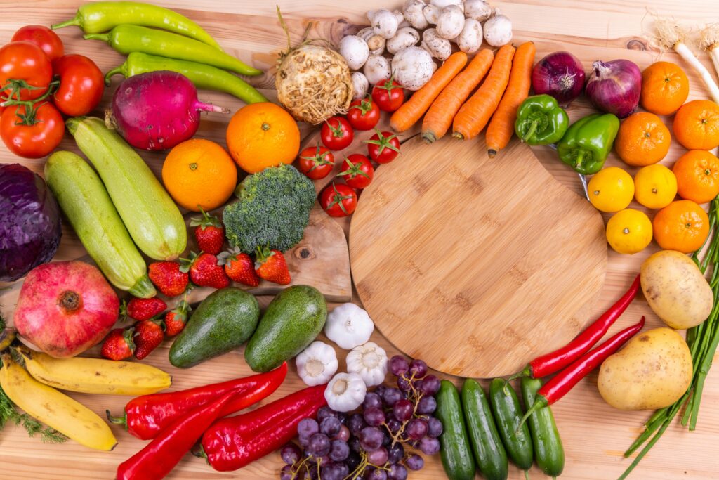 This vibrant image of fresh fruits and vegetables, including tomatoes, avocados, carrots, and broccoli, highlights fiber-rich foods that support gut health.