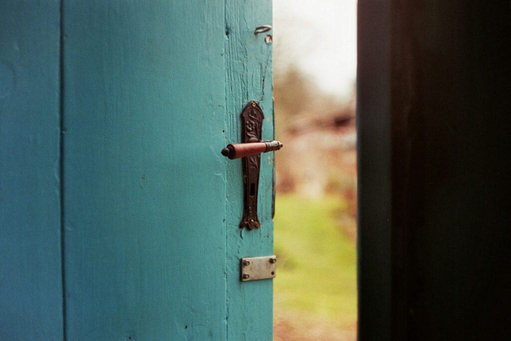 close-up of a partially open blue door with a rustic handle, evoking the idea of unlocking new doors to opportunity.