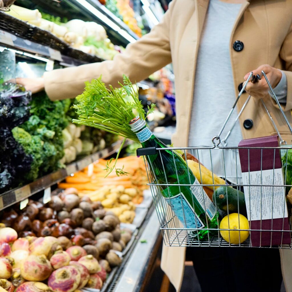 Shopper following biblical healthy eating habits picks fresh vegetables, with a basket full of natural, unprocessed foods and water."