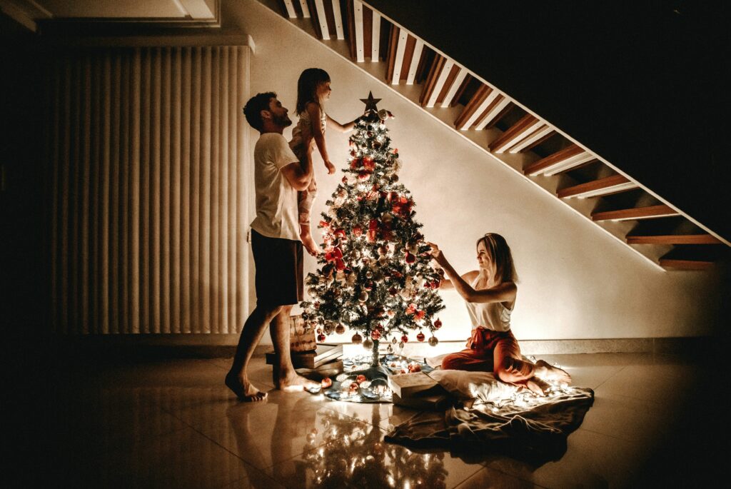 Family decorating a Christmas tree together at home, showcasing a festive holiday activity with twinkling lights and joyful bonding.