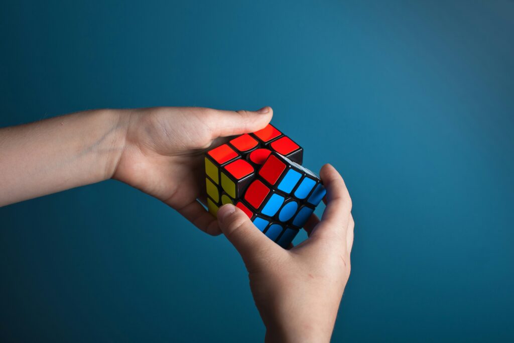 Hands holding a Rubik's Cube against a blue background, symbolizing life’s unsolvable challenges and the need for grace to transform how we face them.