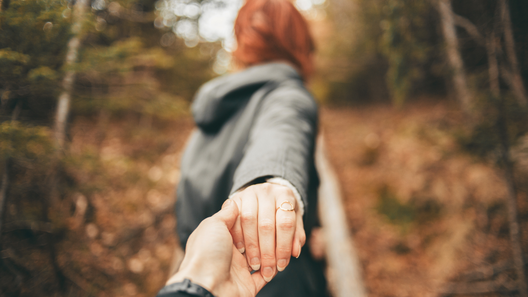 A person leading another by the hand through a wooded path, symbolizing trust and spiritual guidance, representing the concept of being led by the Holy Spirit.
